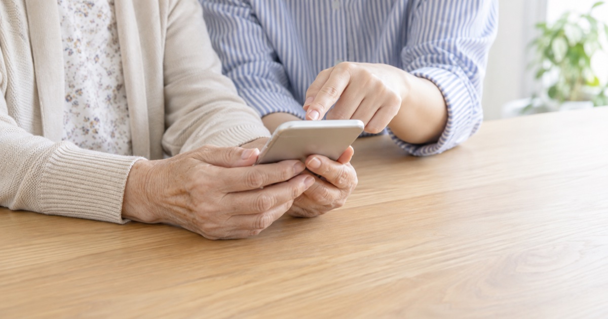 テーブルに並んで座り、スマホを一緒に確認する親子の手元のイメージ